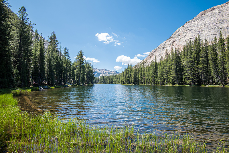 McGee Lake looking southwest, large granite mountains on either side of a long narrow lake with tiny mountains and cloud in the distance.